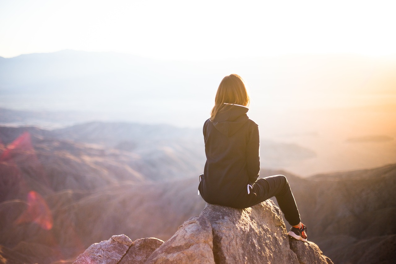 Person in a dark technical jacket on a cliff edge at sunset